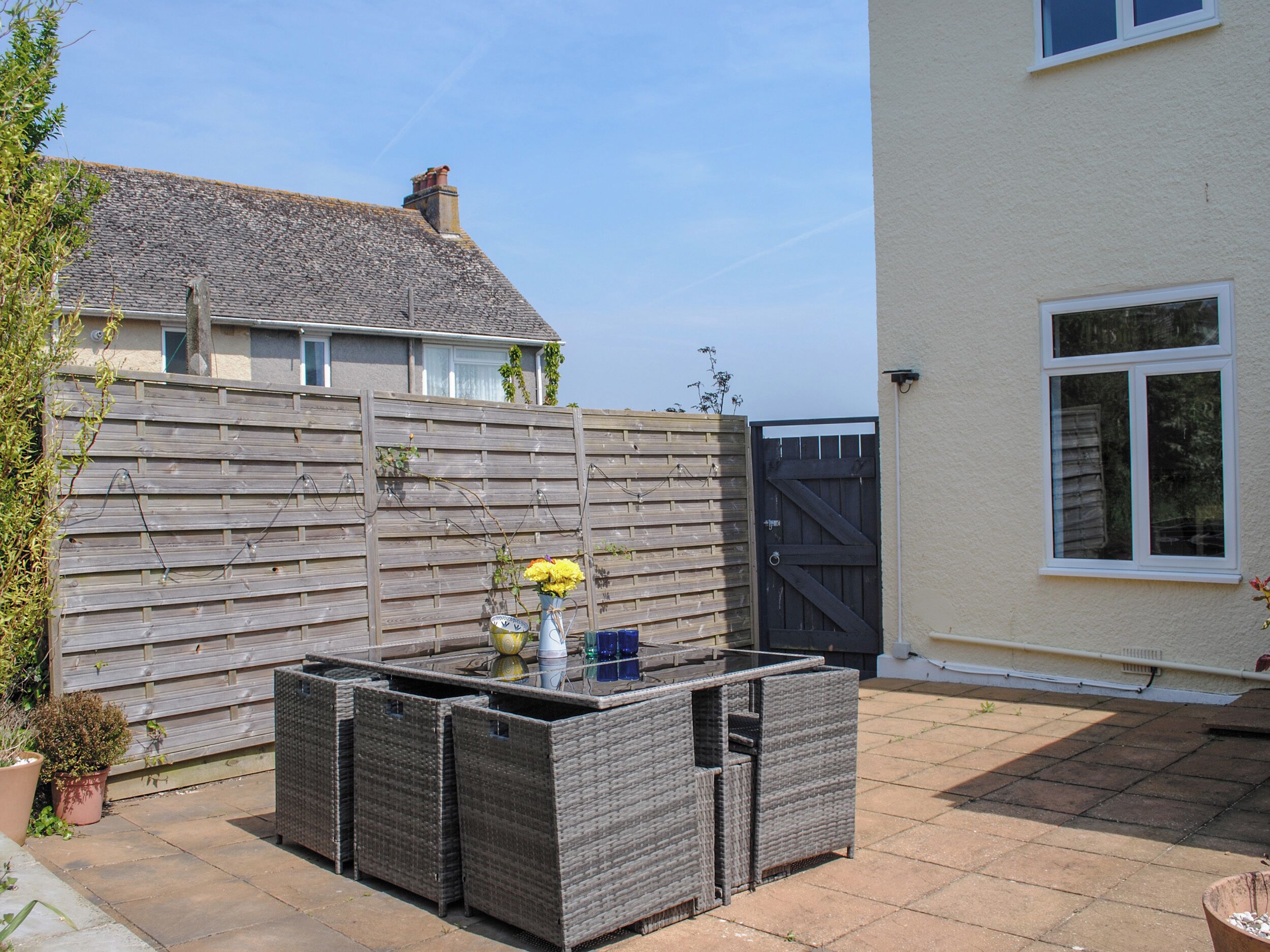 A patio with wicker furniture, a potted plant, and a wooden fence.