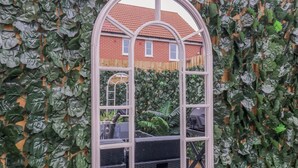 A window with a white frame and multiple panes, surrounded by dense green foliage. - Little Haven (Frinton-on-Sea)