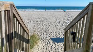 A wooden boardwalk leading to a sandy beach with a clear blue sky. - Sands Beach Club | Ocean & Pool View | Amenities! (Myrtle Beach)