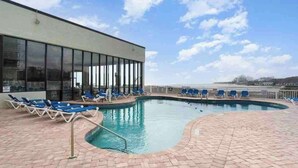 An outdoor swimming pool with lounge chairs and a view of the sea. - Sands Beach Club | Ocean & Pool View | Amenities! (Myrtle Beach)