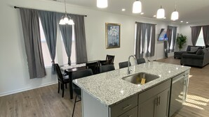 Eine moderne Küche mit einer Granit-Arbeitsplatte, einer Edelstahl-Spüle und Pendelleuchten.