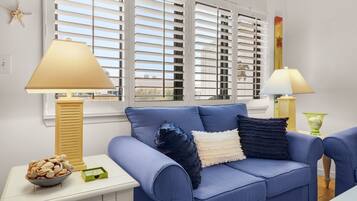 A living room with a blue sofa, two lamps, a starfish decoration, and a bowl of seashells on a side table.