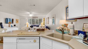 A compact kitchen with a central island, white cabinetry, and a dining area with a sofa and chairs. - 2nd Floor Studio for 4, Pool, 300 Yds to the Beach + Free Attraction Tickets! (Santa Rosa Beach)