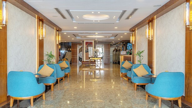 A hotel lobby with a marble floor, blue armchairs with wooden legs, and a central reception desk. - Sweet Home Serviced Apartments (Jeddah)