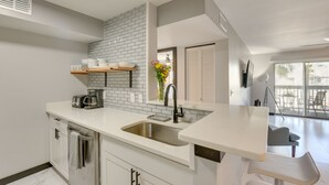 A modern kitchen with white cabinetry, a brick backsplash, and a large window. - Summer Getaway: Destin Condo by Golf & Dining (Destin)