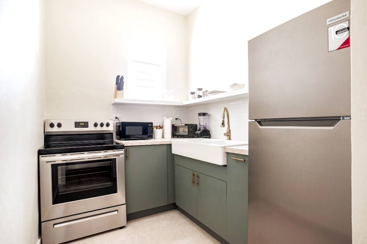 A compact kitchen with a built-in oven, microwave, and a stainless steel refrigerator.