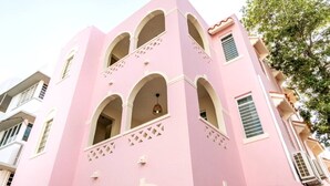 Um edifício rosa com várias varandas e janelas em arco.