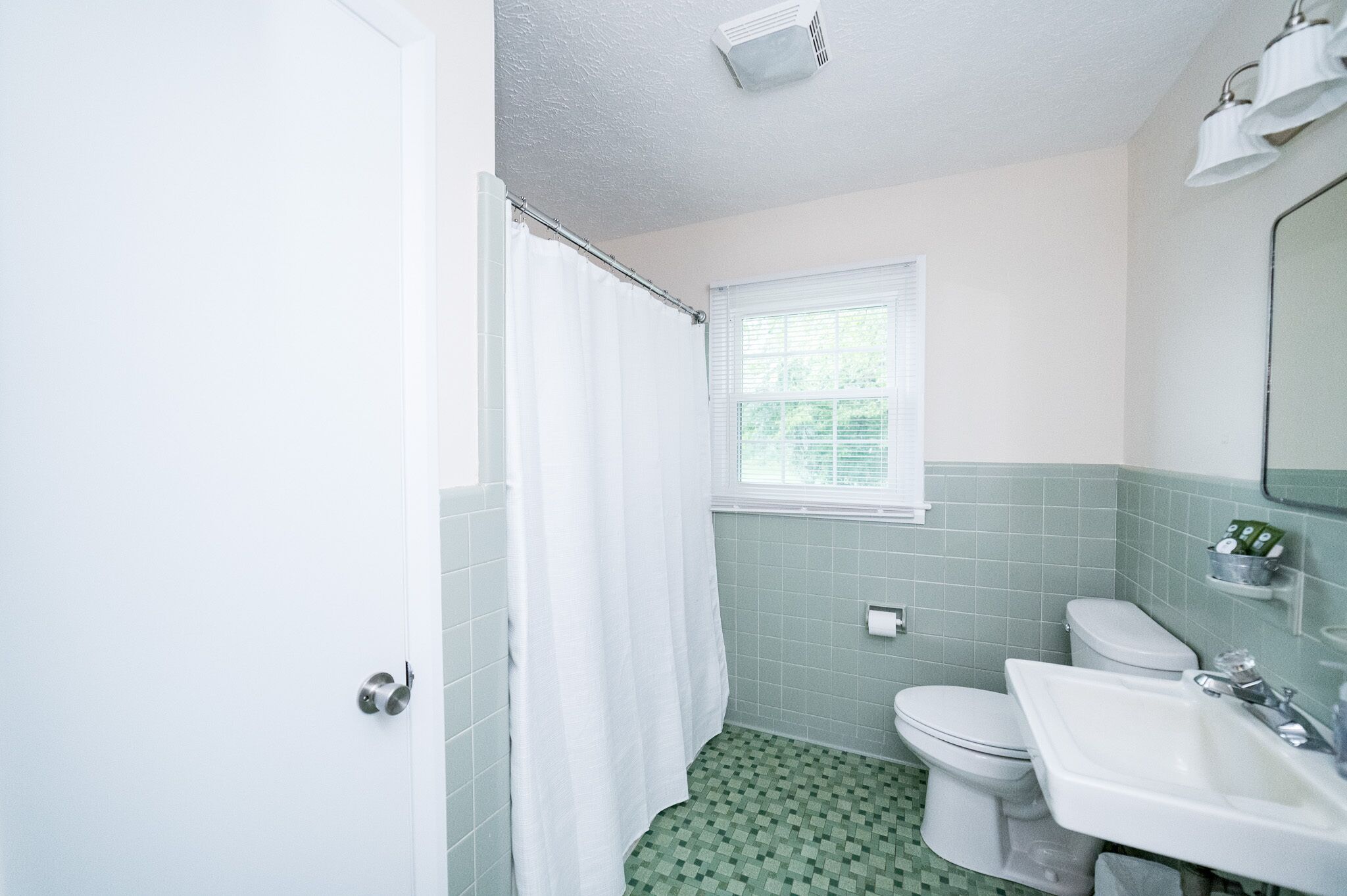 Une salle de bain équipée de toilettes, d’un lavabo et d’un rideau de douche.