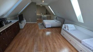 A bedroom with a bed, a dresser, a desk, and a TV. - Happy Moose Guest Suite (Lake Echo)