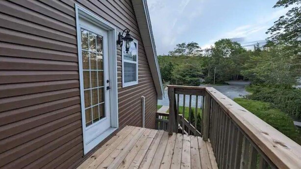 A wooden deck with a railing, a door, and a window. - Happy Moose Guest Suite (Lake Echo)