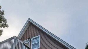 A wooden house with a staircase leading to a porch. - Happy Moose Guest Suite (Lake Echo)