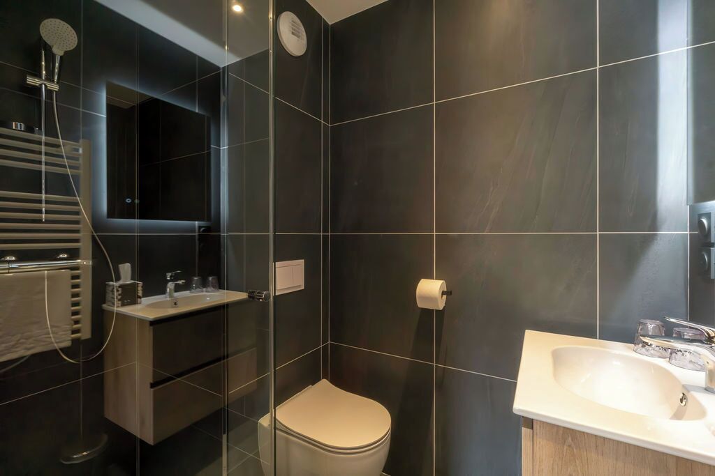 A modern bathroom with a glass-enclosed shower, a toilet, and a vanity with a sink.