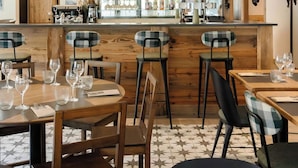 Interior de restaurante con mostradores de madera, sillas a cuadros y suelo de baldosas.