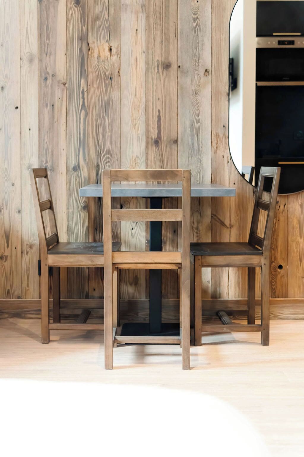 A wooden dining table with two chairs, set against a wooden wall.