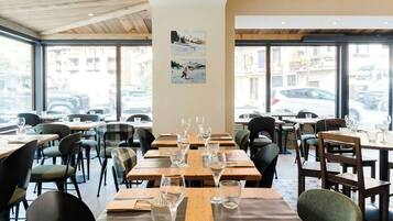A restaurant with multiple tables and chairs, large windows, and artwork on the wall.