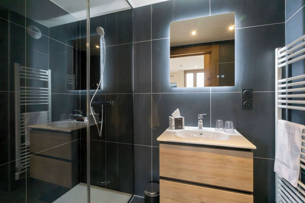 Une salle de bain moderne avec une douche à parois de verre, un meuble-lavabo avec un miroir et un porte-serviettes.