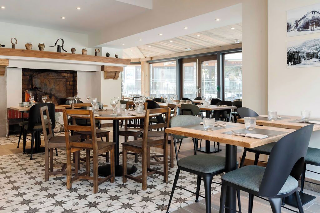 Un restaurant avec des tables et des chaises en bois, un sol à motifs et une cheminée.