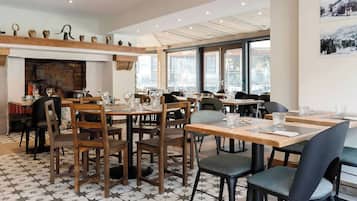 Een restaurant met houten tafels en stoelen, een vloer met patroon en een open haard.
