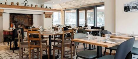 A restaurant with wooden tables and chairs, a patterned floor, and a fireplace.