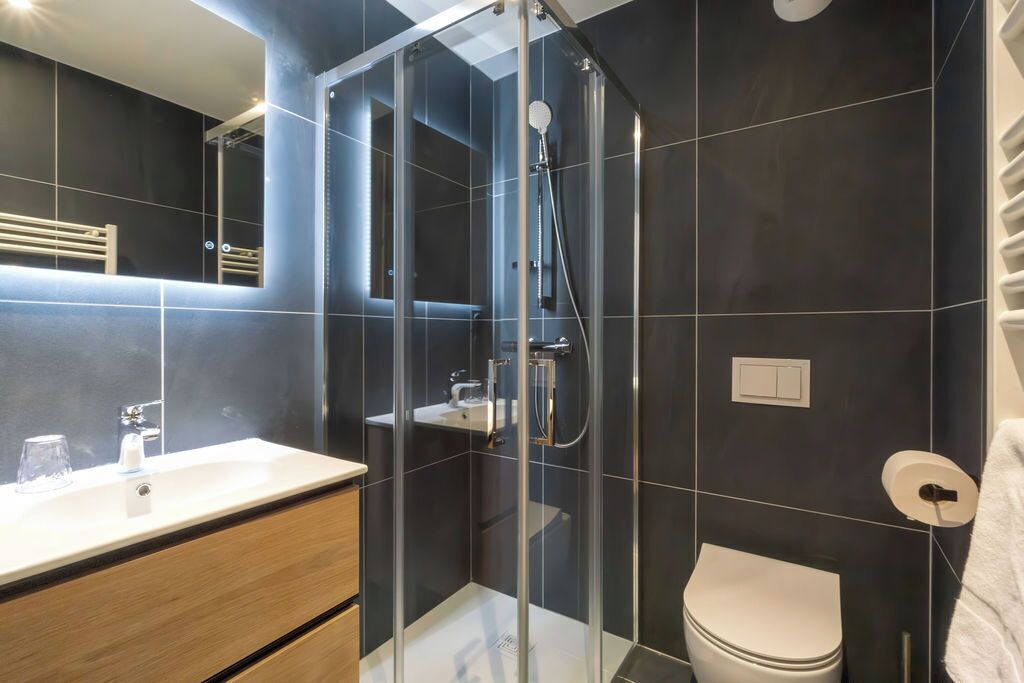 A modern bathroom with a glass-enclosed shower, a white sink, and a toilet.