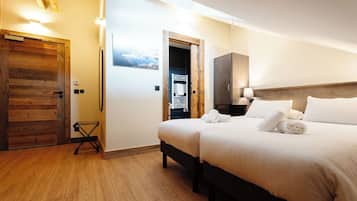 Une chambre d’hôtel avec une porte en bois, un lit avec du linge de maison blanc, une table de chevet et un radiateur fixé au mur.