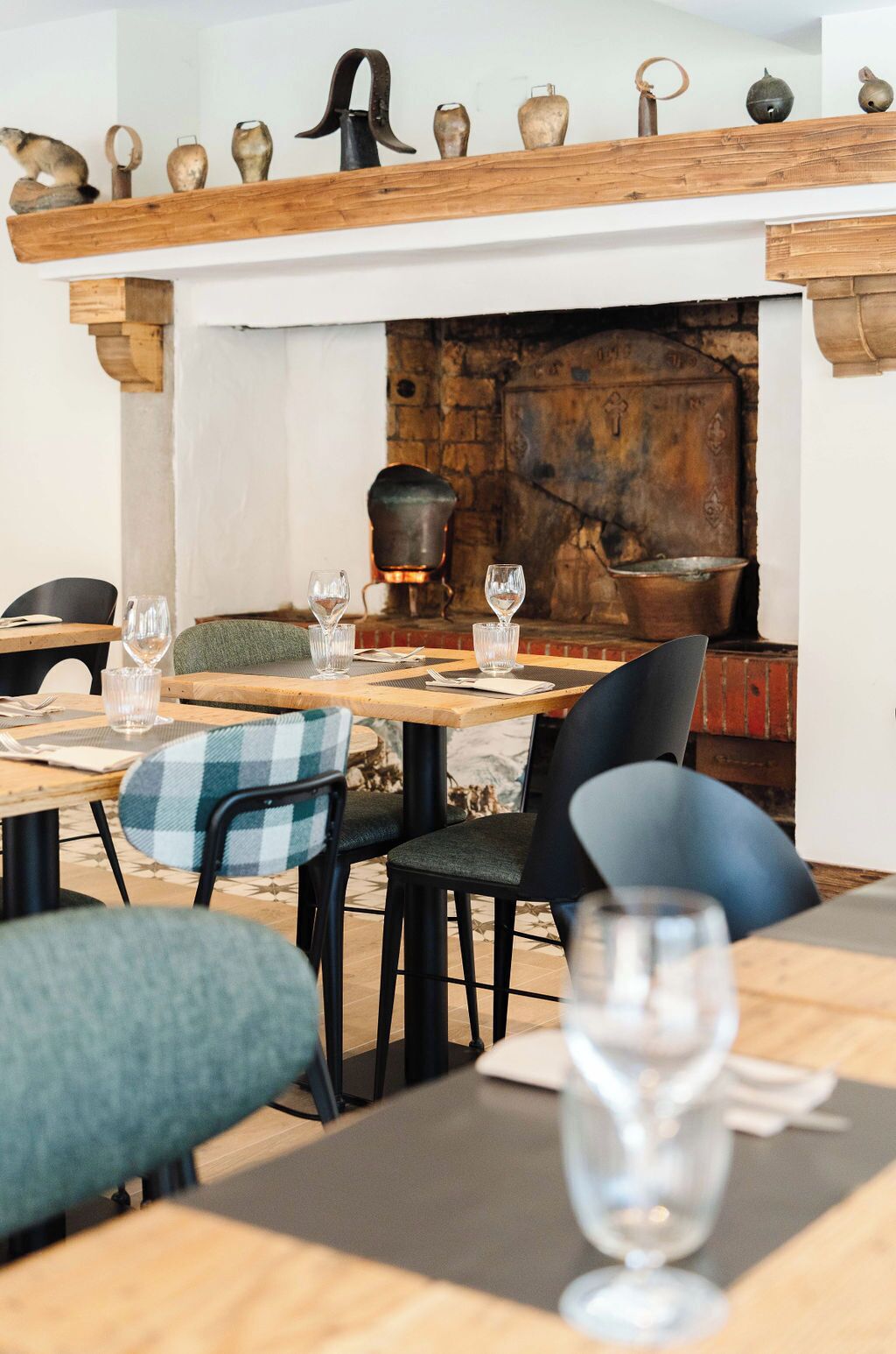 L’intérieur d’un restaurant avec des tables en bois, des chaises noires et une cheminée en briques.