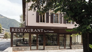 Un restaurante llamado "RESTAURANT La Cozna" con fachada de piedra y amplios ventanales.