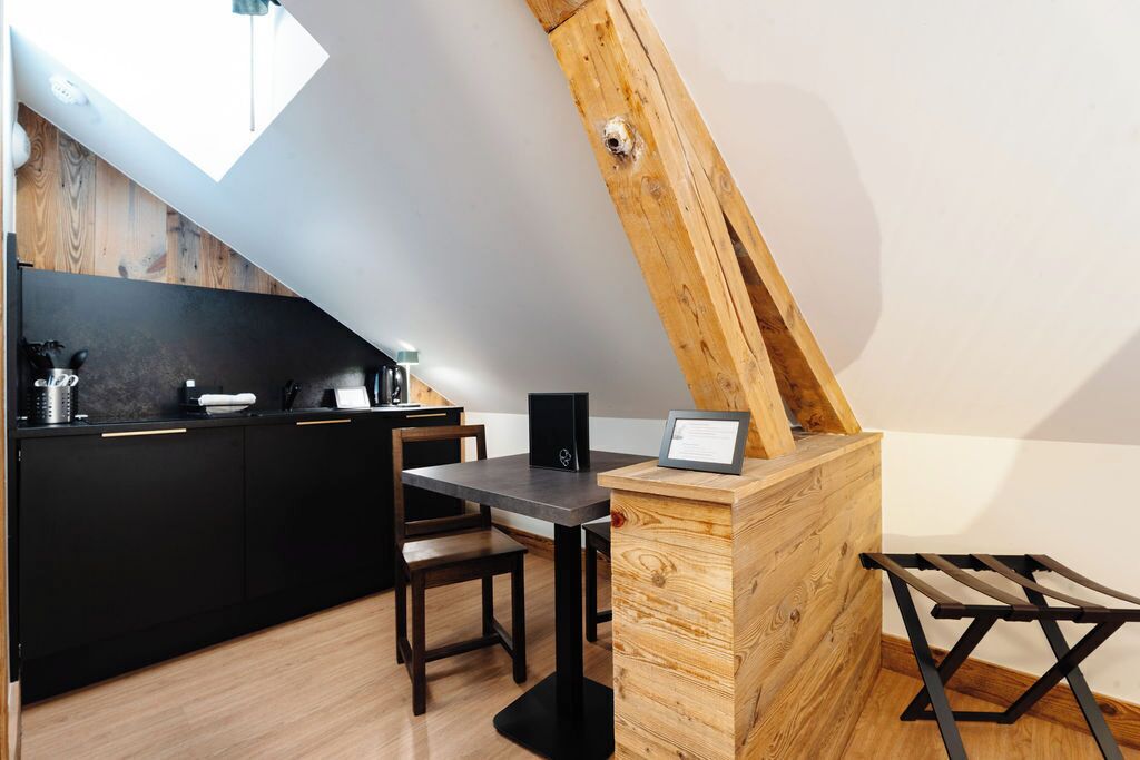 Una cocina moderna con encimera negra, armarios de madera y una mesa de comedor de madera.