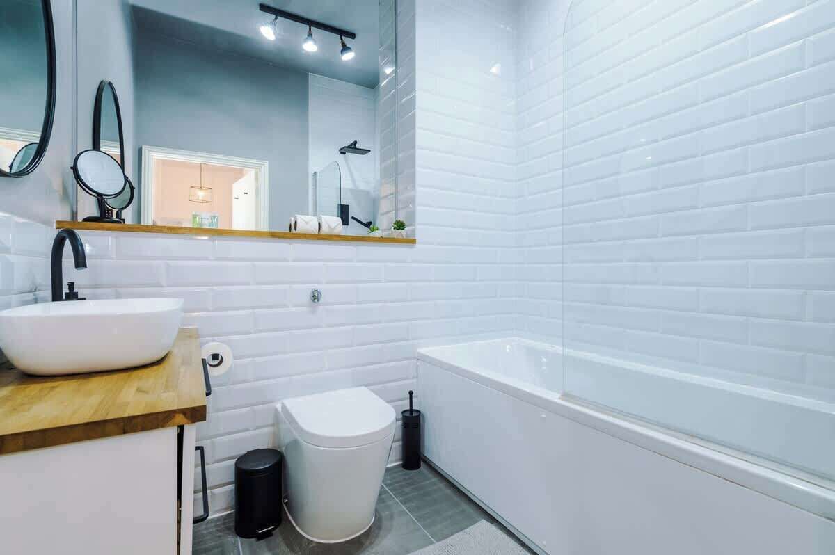 Een moderne badkamer met een wit wastafel, spiegel en bad.