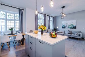 Une cuisine moderne dotée d’un îlot central, d’un coin repas et d’un espace de vie comprenant un canapé et un tableau.