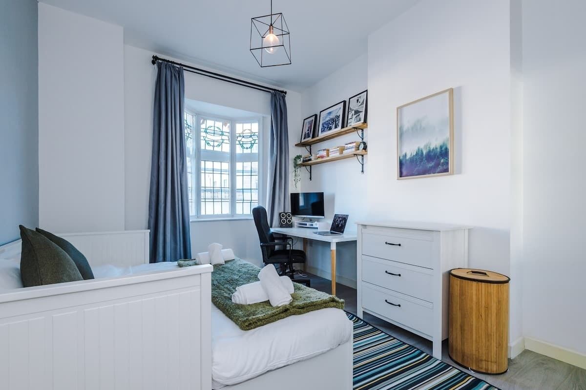 Een moderne slaapkamer met een bed, bureau en computer.