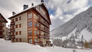 A multi-story wooden building with balconies, set against a snowy mountain backdrop. - Val de Ruda Luxe 10 by FeelFree Rentals (Baqueira)