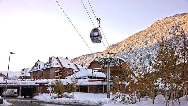 A ski lift in operation, a building with a sloped roof, and a snow-covered mountain in the background. - Val de Ruda Luxe 10 by FeelFree Rentals (Baqueira)