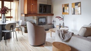 A cozy living room with a stone fireplace, wooden ceiling beams, a flat-screen TV, and a comfortable seating area with a sofa and chairs. - Val de Ruda Luxe 10 by FeelFree Rentals (Baqueira)