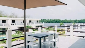 A balcony with a table and chairs, overlooking a body of water and greenery. - NEW Bayfront Villa in Costa del Sol

 (El Zapote)