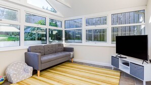 A modern living room with a grey sofa, a flat-screen TV, and large windows. - Tre Lowen (Port Isaac)