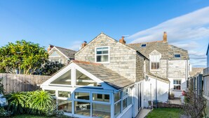 A house with a conservatory, a fenced backyard, and a stone exterior. - Tre Lowen (Port Isaac)