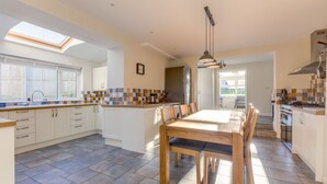 A spacious kitchen with a large island, modern appliances, and ample natural light from skylights. - Tre Lowen (Port Isaac)
