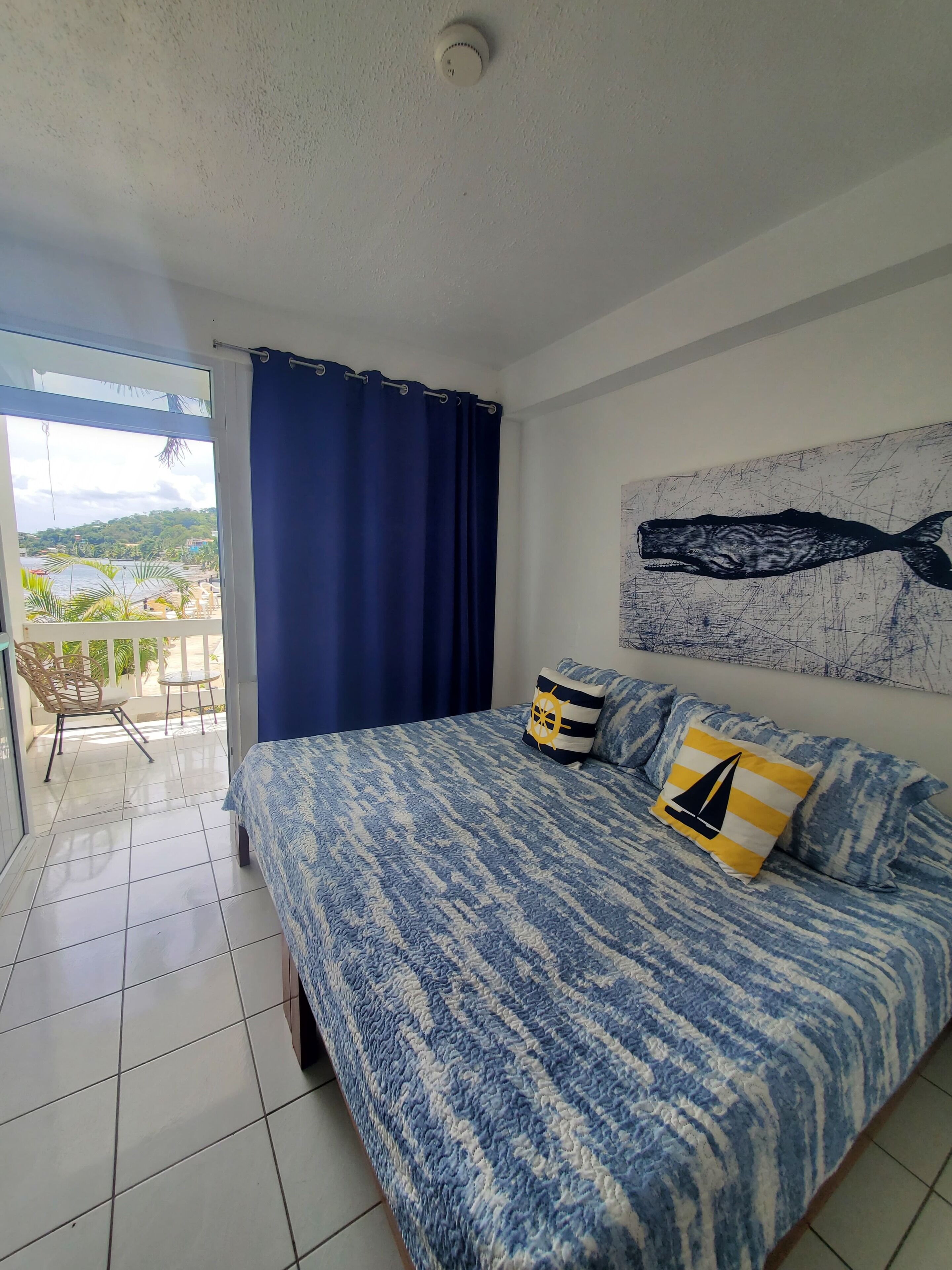 Ein Schlafzimmer mit Bett, Ausblick ins Freie und Deckenleuchte.