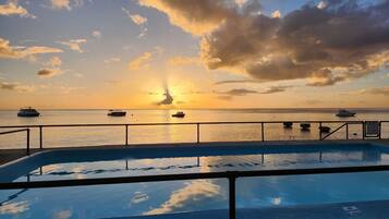 Una piscina con vistas a barcos en el agua al atardecer.