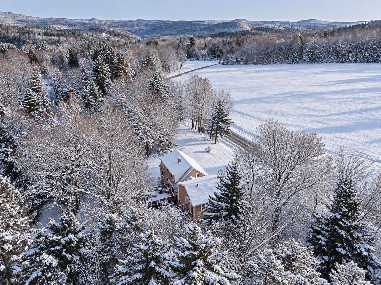 A snow-covered landscape with a house surrounded by trees.