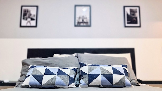 A bed with two pillows, a nightstand, and three framed pictures on the wall. - Bauten Cabo Branco - By EasyHost (João Pessoa)