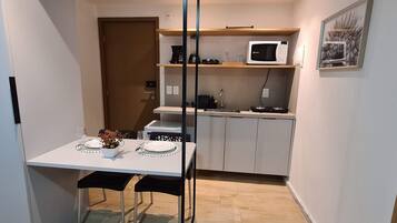 Una cocina compacta con microondas, cafetera y pileta.