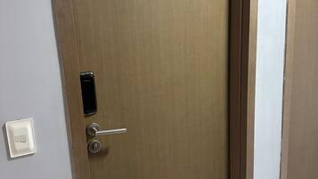 Una puerta cerrada con teclado numérico, un interruptor de luz en la pared y el número '405' en la pared contigua.