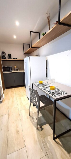 Cocina moderna con comedor, que incluye una mesa con sillas, un refrigerador y una cafetera.