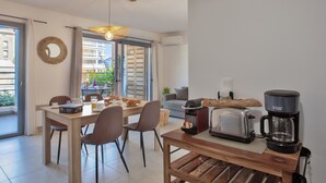 A modern kitchen with a dining area, a coffee maker, a toaster, and a view of the outside. - Appartement "Fiora" en centre-ville de Calvi - 2 4 personnes (Calvi)