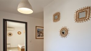 A hallway with a bed, a mirror, and wall art. - Appartement "Fiora" en centre-ville de Calvi - 2 4 personnes (Calvi)