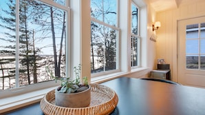 Ein Zimmer mit großen Fenstern, einem gewebten Korb mit Pflanzen und einer Wandleuchte.