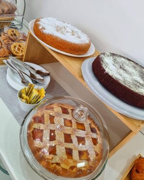 A variety of baked goods including a pie, a cake, and pastries on a serving table. - HOTEL CRISVAN (Rimini)