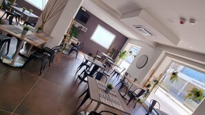 A spacious dining area with multiple tables and chairs, large windows providing natural light, and a modern interior design. - HOTEL CRISVAN (Rimini)